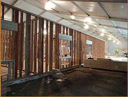  Interior of a spacious construction tent with exposed framework and overhead lighting, indicating an ongoing project site.